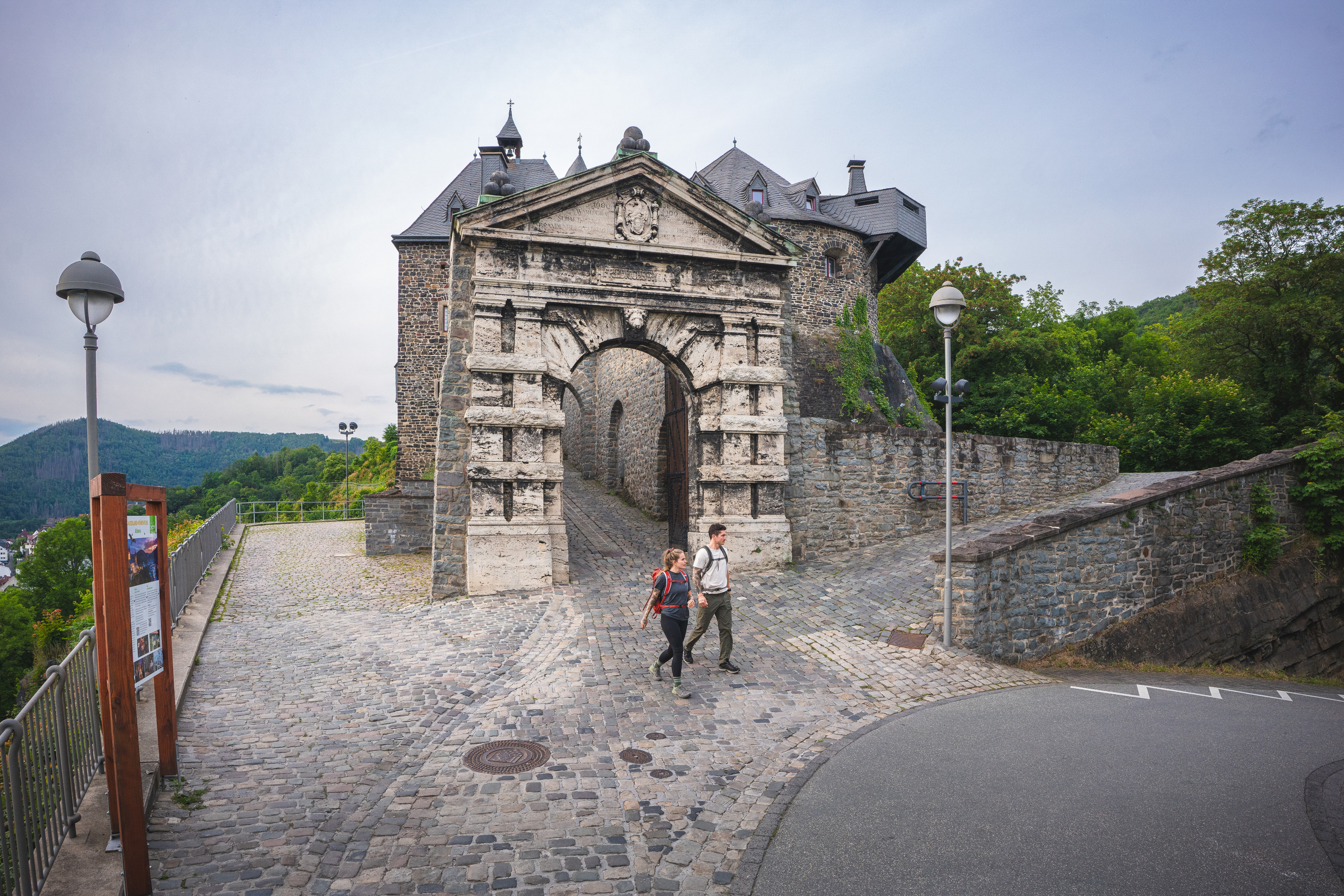 Zwei Wanderer am Burgtor der Burg Altena am Startpunkt vom Sauerland-Höhenflug